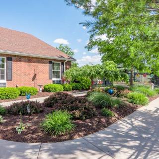 A charming brick house with beautifully landscaped gardens and a winding sidewalk.
