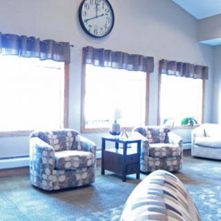 A cozy living room with armchairs and a large wall clock.