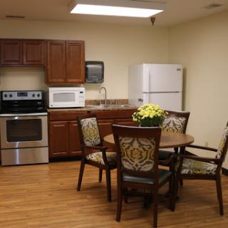 A cozy kitchen and dining area featuring modern appliances and a round table with decorative chairs.