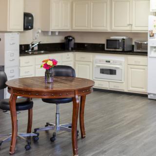 A cozy kitchen with a wooden table and chairs, surrounded by modern appliances and white cabinets.