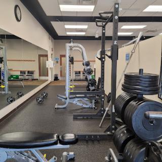 A well-equipped gym space featuring various workout machines and weights, ideal for strength training and fitness.
