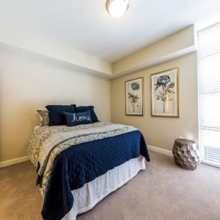 A modern bedroom featuring a neatly made bed with blue and white bedding, complemented by decorative artwork on the walls.
