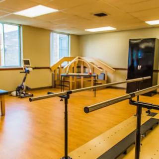 A physical therapy room with exercise equipment and parallel bars.
