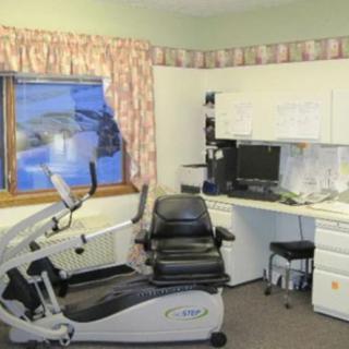 A small office space featuring an exercise bike and a desk with a computer setup.