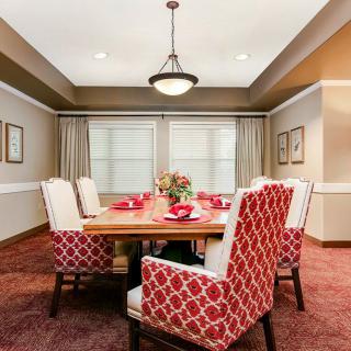A cozy dining room with red patterned chairs and elegant lighting.
