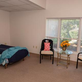 A cozy bedroom with a bed, chairs, and a window offering a scenic view.