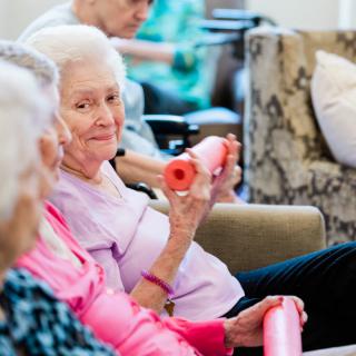 Elderly women participating in a group exercise session with small weights.