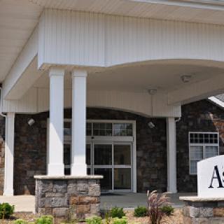The entrance of a modern facility featuring stone and architectural columns.