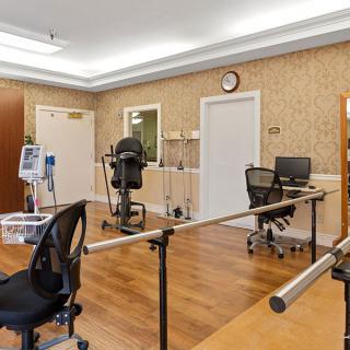 A rehabilitation therapy room equipped with exercise machines and parallel bars.