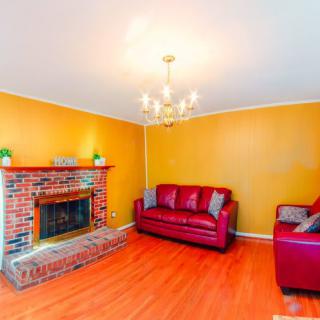A cozy living room with red sofas and a brick fireplace, featuring yellow walls and a chandelier.