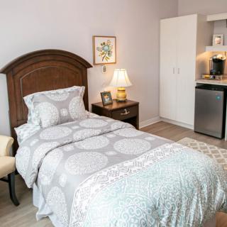 A cozy bedroom with a single bed, nightstand, and soft lighting.