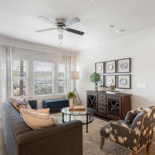 A modern living room with a comfortable sofa, artwork on the walls, and ample natural light from large windows.