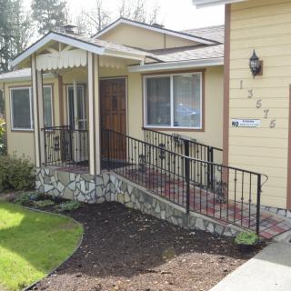 A yellow house with an accessible ramp leading to the front porch.