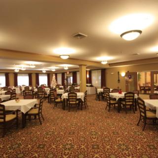 A spacious dining hall with neatly arranged tables and chairs on a carpeted floor.