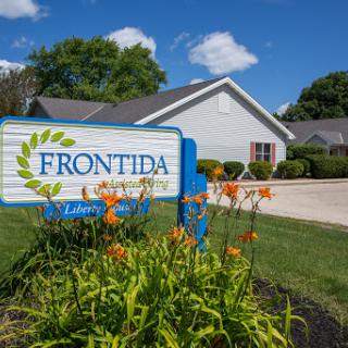 Entrance to Frontida, featuring a welcoming sign and vibrant flowers in the foreground.