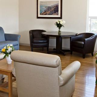A cozy living room with comfortable seating, a small table with flowers, and a framed picture on the wall.
