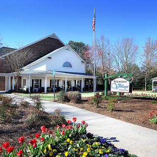 A welcoming building entrance flanked by a garden with colorful flowers.