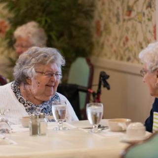 Elderly individuals enjoying a conversation over a meal in a cozy setting.