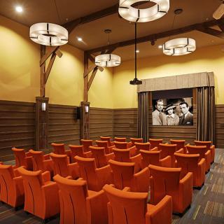 A cozy cinema with orange seats and a classic movie on the screen.