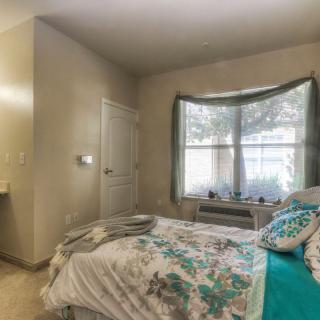 A cozy bedroom with a bed, window, and natural light filtering in.