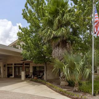 A building entrance surrounded by lush greenery and an American flag.