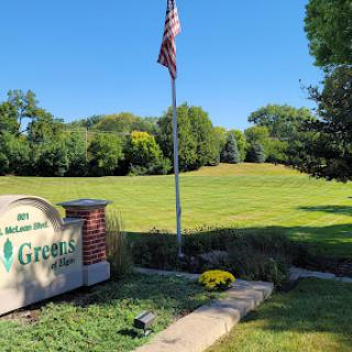 A serene view featuring a flag and a well-maintained golf course under a clear blue sky.