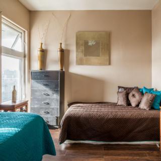 A modern bedroom with two beds, featuring elegant decor and wooden flooring.