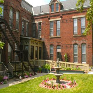 A historic brick building with an inviting courtyard featuring a central fountain and garden.