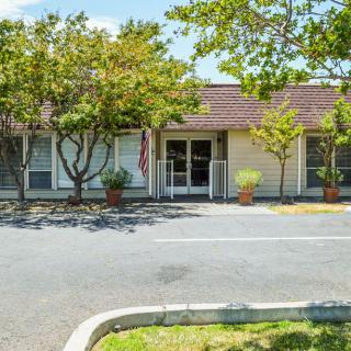 Small building with trees and a parking lot in front.