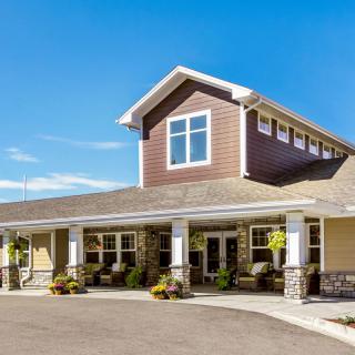 A modern residential building with a gabled roof and stone accents under a clear blue sky.