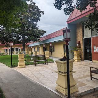 A serene outdoor space featuring a well-maintained building, benches, and landscaped greenery.