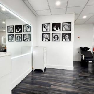 A modern hair salon interior featuring wall portraits and sleek design elements.