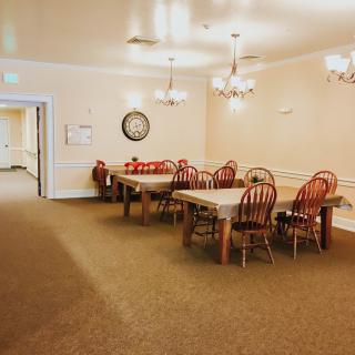 A cozy dining area with wooden tables and chairs, illuminated by chandeliers.