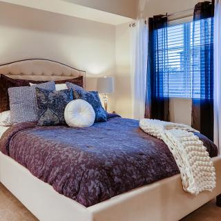 A cozy and well-decorated bedroom with a plush bed and stylish pillows.