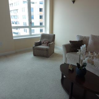 A cozy living room featuring a comfortable sofa and armchair with ample natural light from the large window.