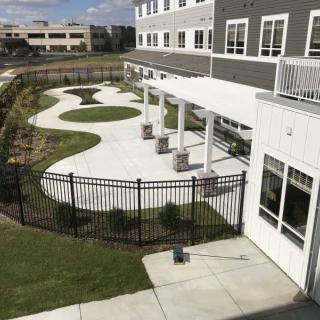 A modern building with a landscaped garden and pathway enclosed by a fence.