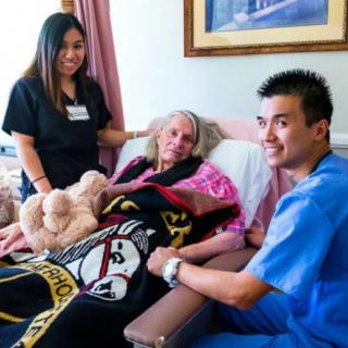 Medical staff assisting an elderly patient in a hospital room.