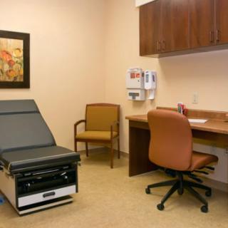 A clean and organized doctor's exam room with medical equipment and seating.