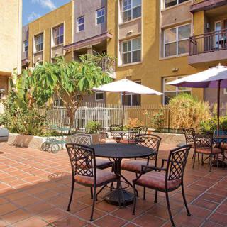 A sunny outdoor patio with tables and umbrellas in an apartment complex.