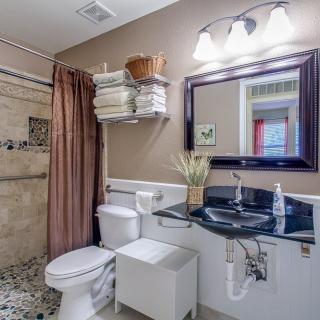 A well-organized bathroom featuring a shower, sink with countertop, and neatly arranged toiletries.