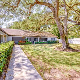 A charming house with a large tree and well-maintained lawn.