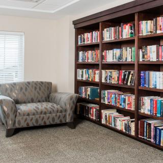 A cozy reading nook with a large bookshelf filled with books and a comfortable armchair.