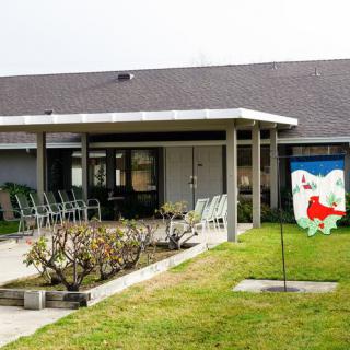 A house with a covered patio, outdoor seating, and a neatly maintained garden.