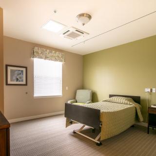 A simple and clean hospital room with a single bed and a chair.