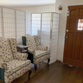 A cozy living room corner with floral patterned chairs and a screen divider.
