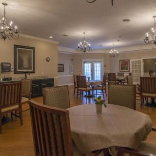 A cozy dining room with wooden tables and chairs, adorned by elegant chandeliers.