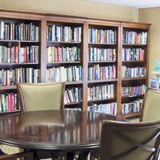 A cozy reading room with bookshelves and a round table surrounded by chairs.