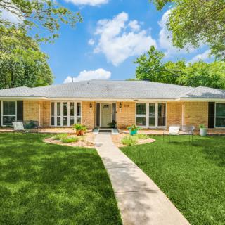 A charming brick house with a well-maintained lawn and a clear blue sky.