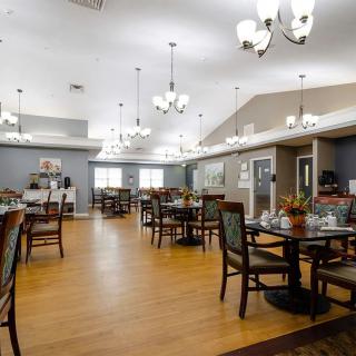 A spacious dining area with neatly arranged tables and chairs, illuminated by elegant chandeliers.