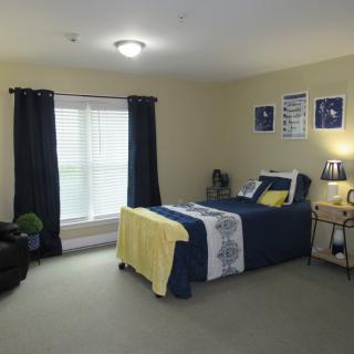 A cozy and well-decorated bedroom with a neatly made bed, dark curtains, and soft lighting.